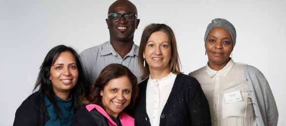 5 staff members in a group smile at the camera