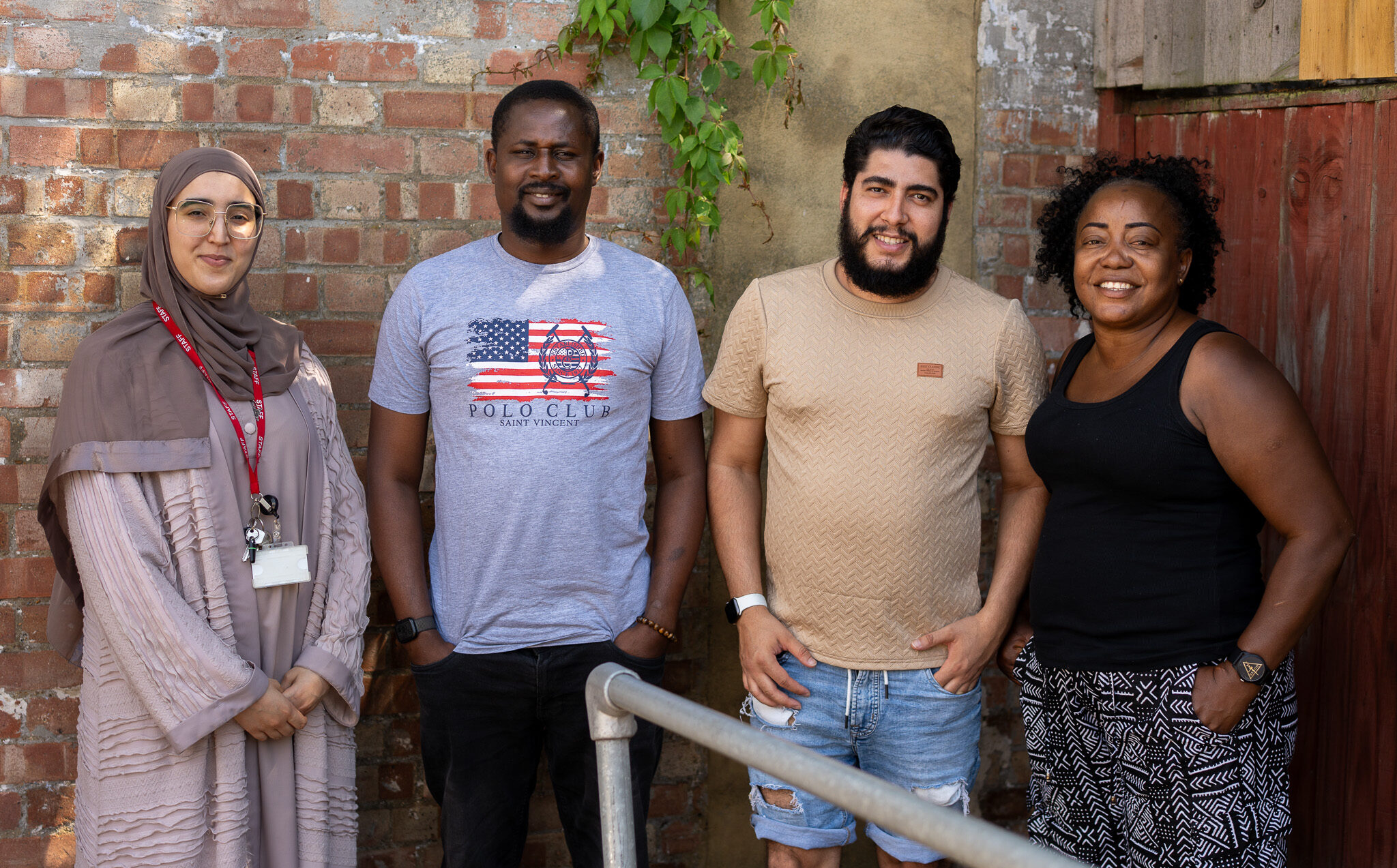 A group of four staff members in front of the garden wall at Stratford Road.
