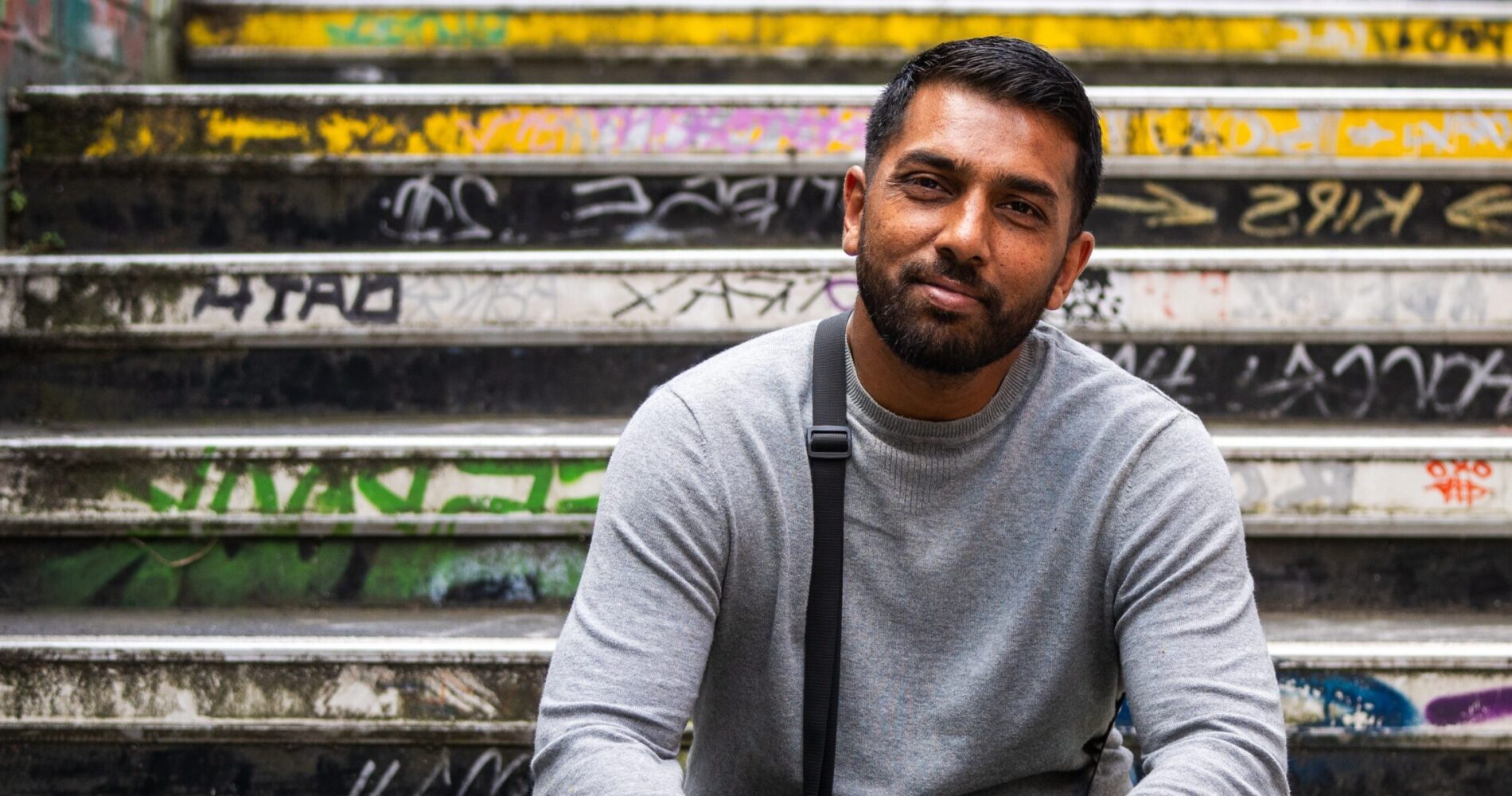 A former Look Ahead customer sits on a graffiti-covered staircase smiling.