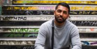 A former Look Ahead customer sits on a graffiti-covered staircase smiling.