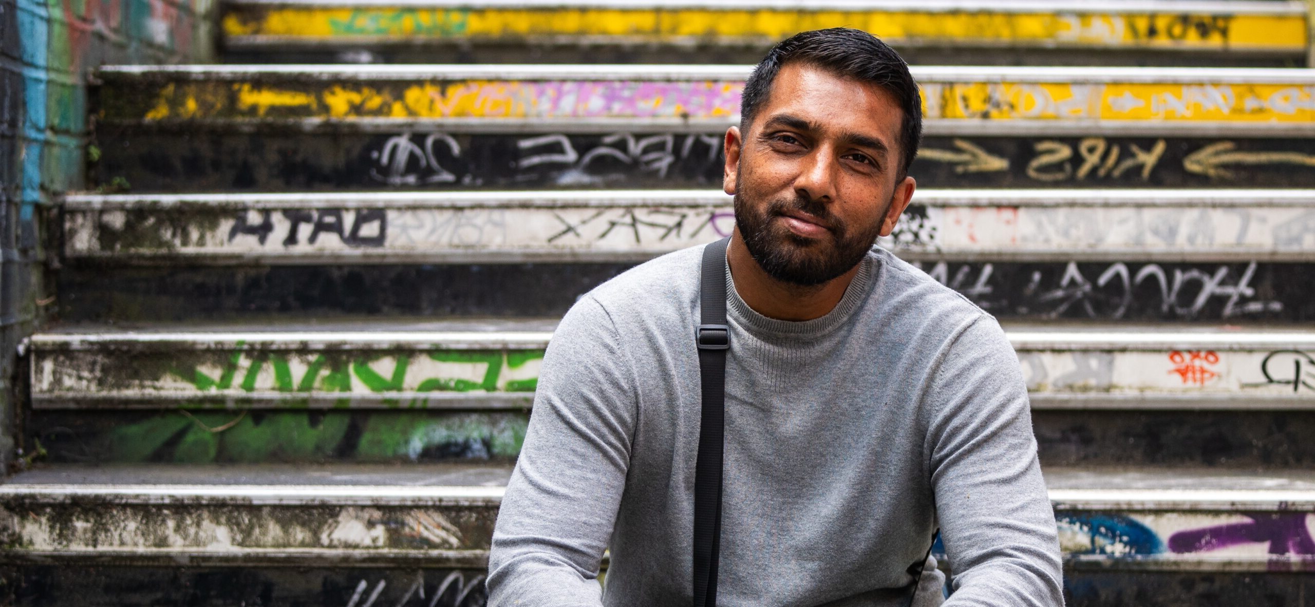 A former Look Ahead customer sits on a graffiti-covered staircase smiling.