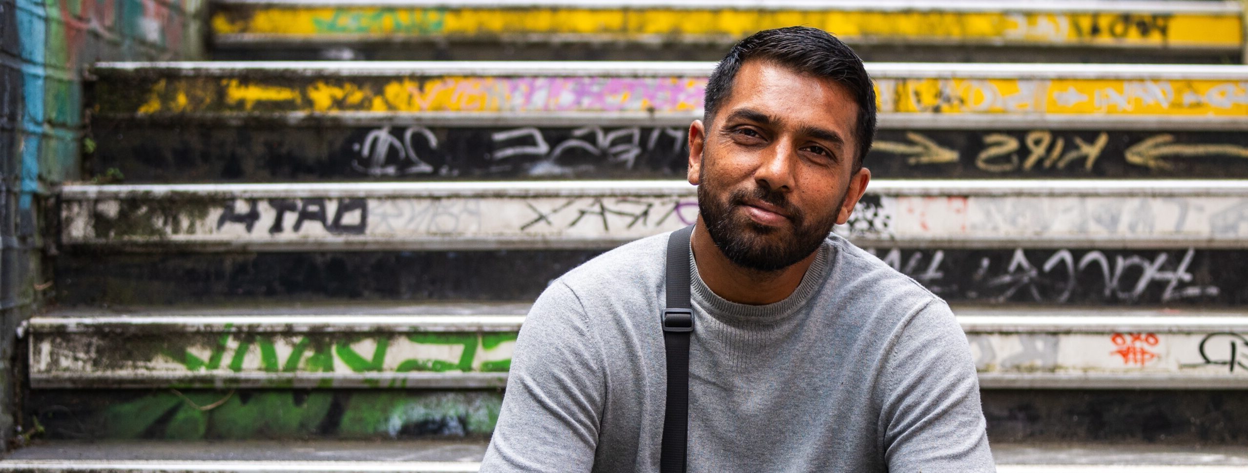 A former Look Ahead customer sits on a graffiti-covered staircase smiling.