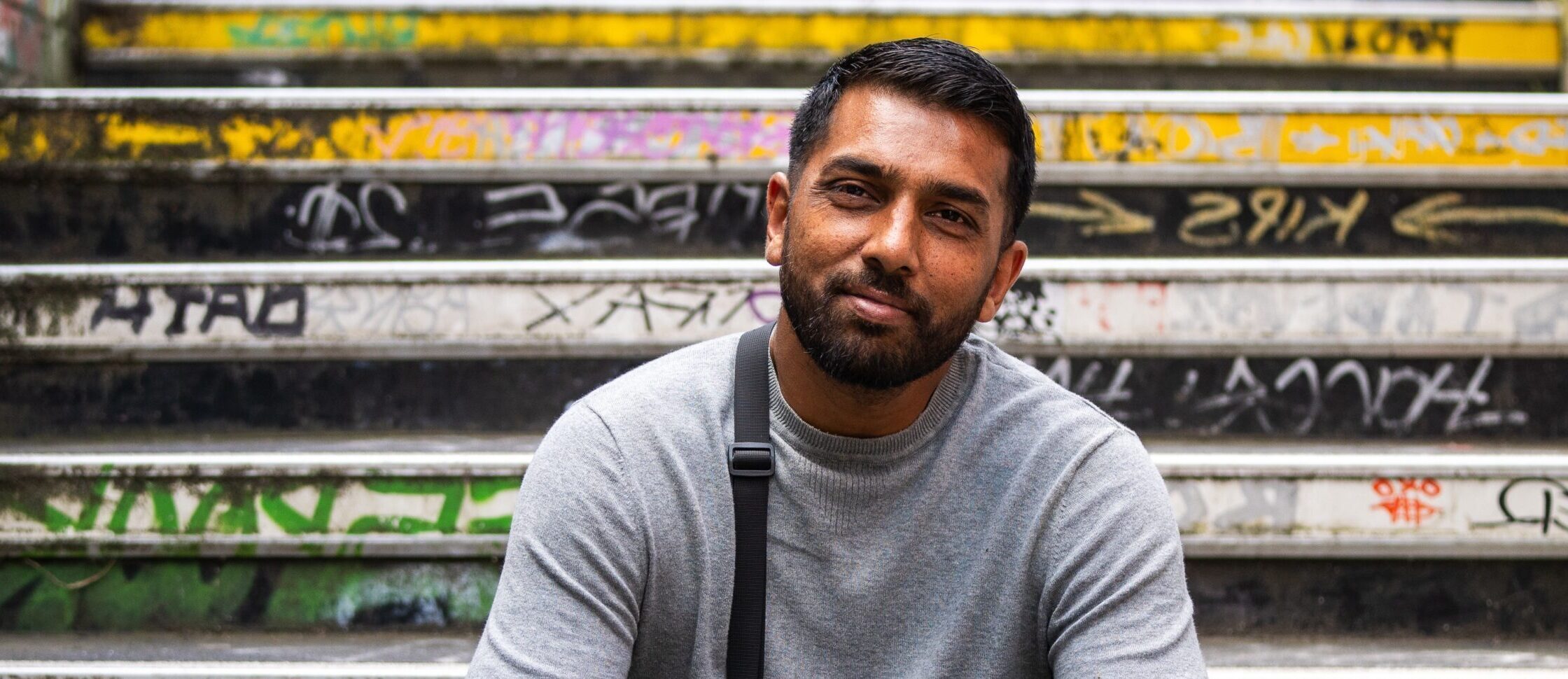 A former Look Ahead customer sits on a graffiti-covered staircase smiling.