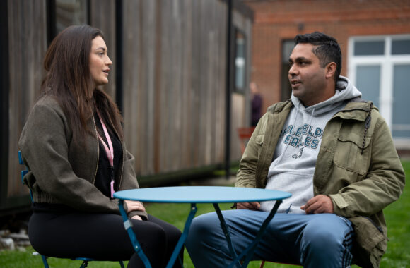 A male customer sitting at a table chatting with a female support worker.