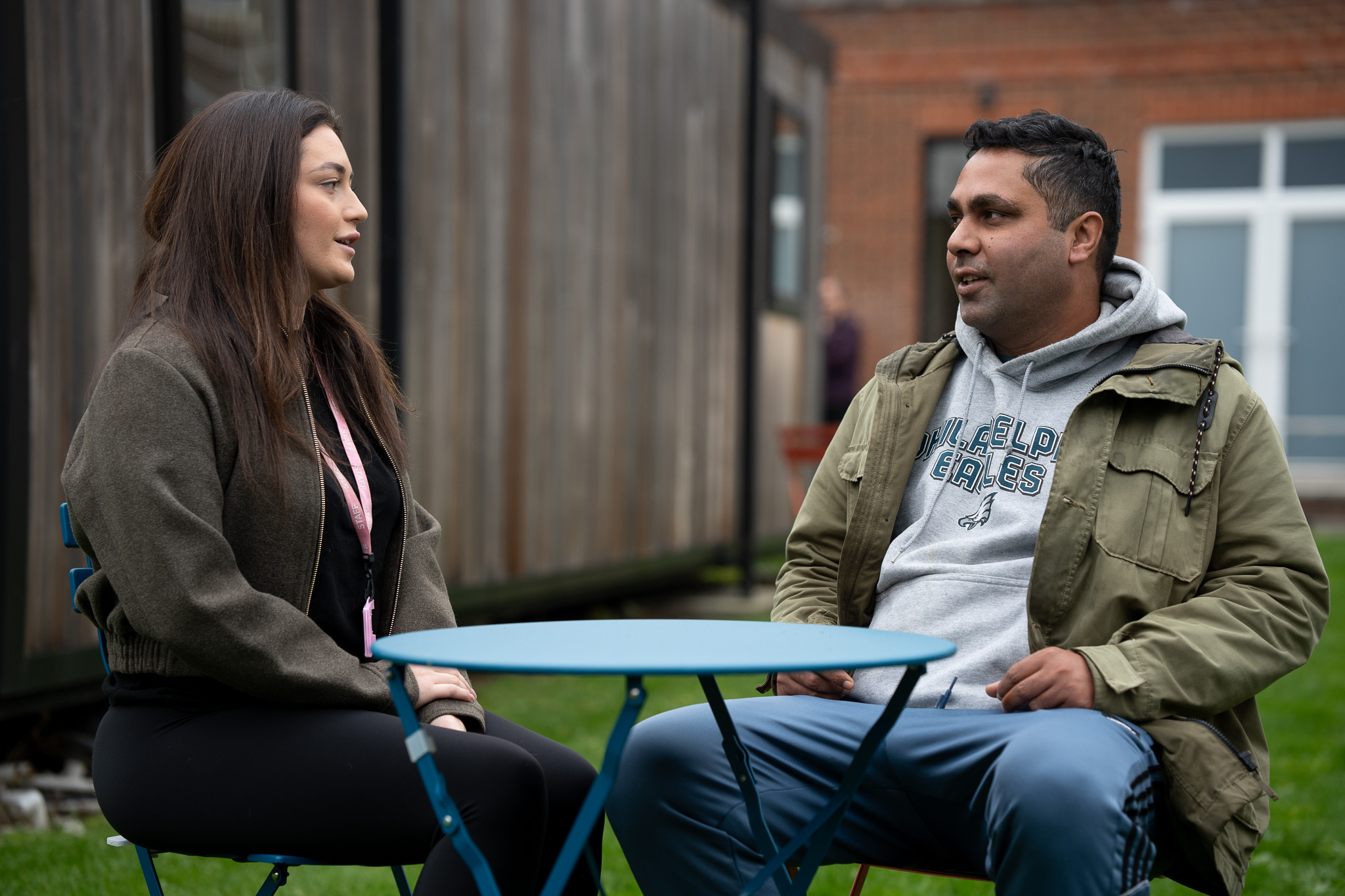 A male customer sitting at a table chatting with a female support worker.