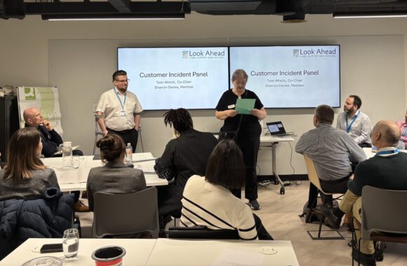 Members of Look Ahead's customer incidents panel present to an audience standing in front of a PowerPoint presentation.
