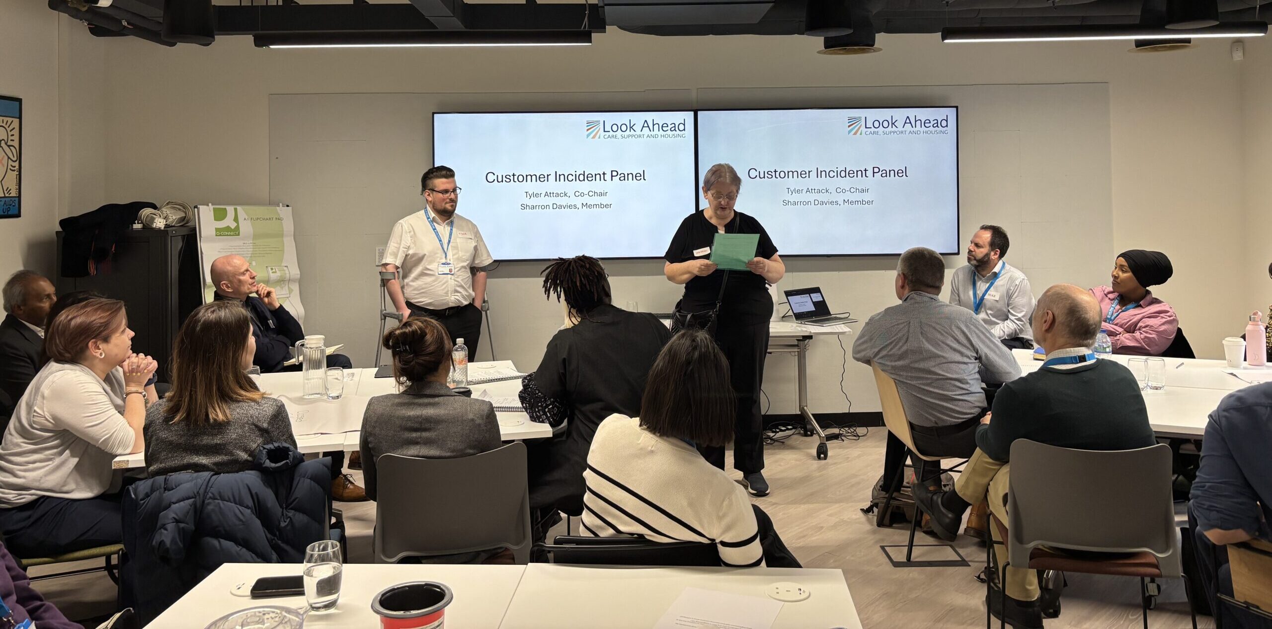 Members of Look Ahead's customer incidents panel present to an audience standing in front of a PowerPoint presentation.