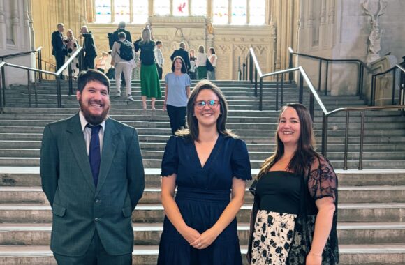 Two Look Ahead domestic abuse staff members standing either side of a Kent MP in Parliament.