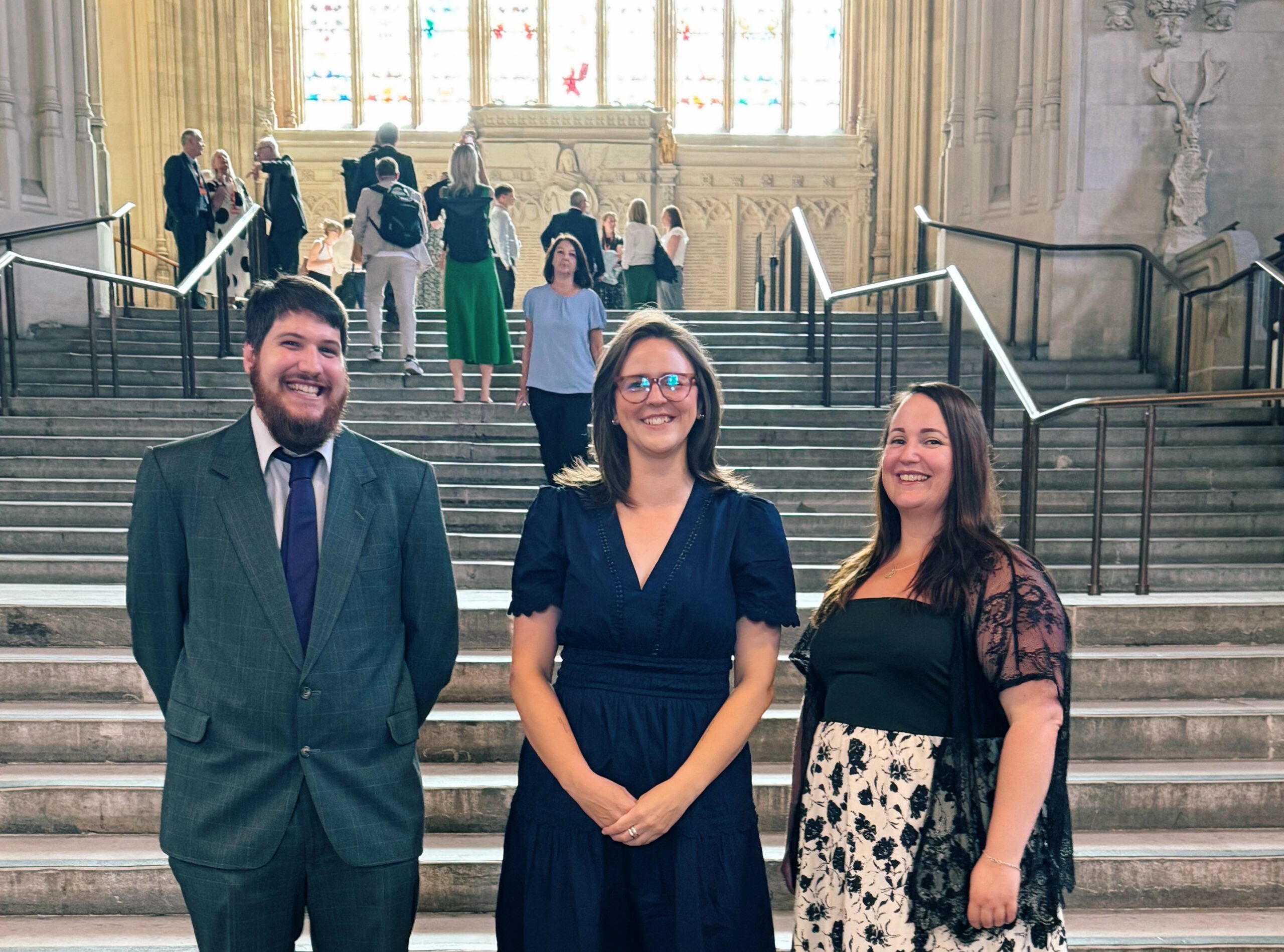Two Look Ahead domestic abuse staff members standing either side of a Kent MP in Parliament.
