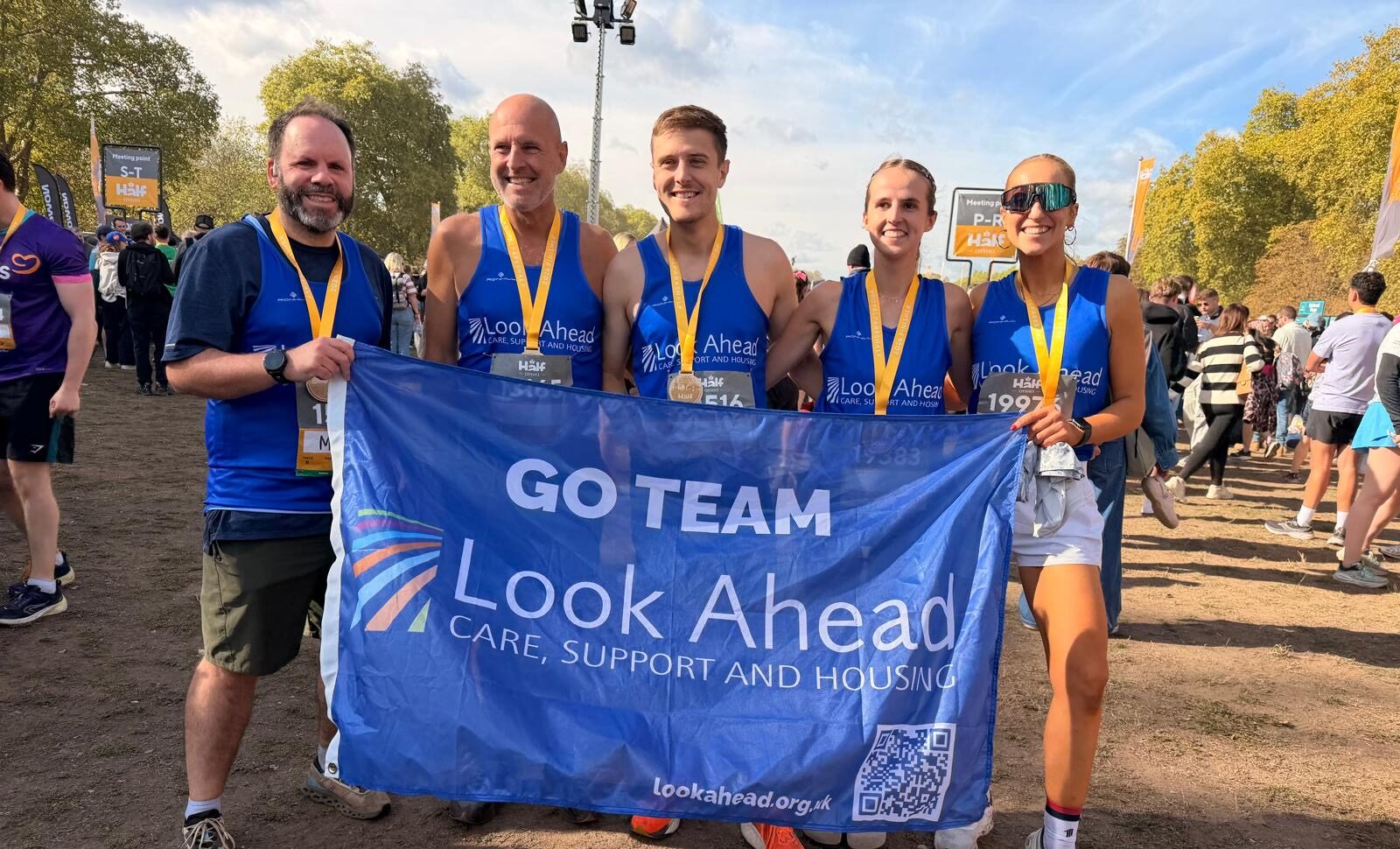 Five runners gather behind a blue Look Ahead flag with Go Team written on it, and a Look Ahead logo.